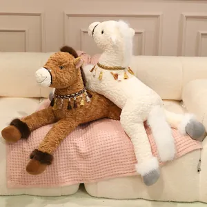 Pair of cute plush horse toys with tassel collars resting on a cozy sofa