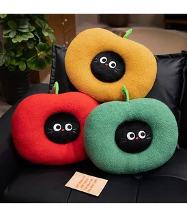 Close-up of three colorful apple-shaped plush cushions with cute cat faces on a sofa