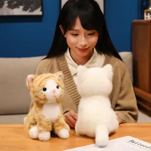 Primo piano di gatti di peluche realistici bianco e arancione a strisce sul tavolo.