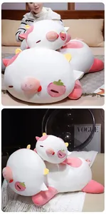 Detailed view of soft strawberry cow pig plush toy on a white knitted sofa throw.