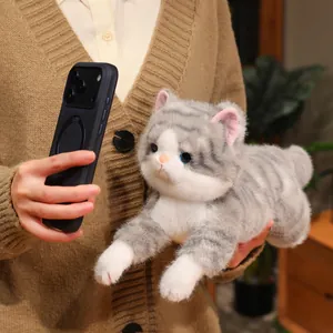Primo piano di un gattino di peluche grigio realistico tenuto da una persona in un interno