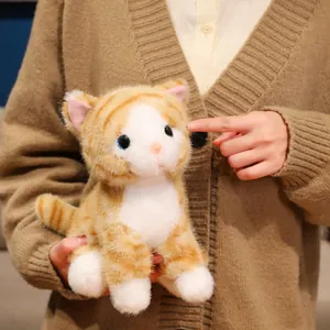 Dettaglio ravvicinato di un morbido gatto di peluche soriano tenuto e toccato con le mani