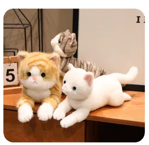 Peluche di gatto realistici nei colori arancione, tigrato e bianco su una scrivania