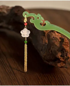 Dettaglio di un fermaglio per capelli cinese verde con fiore di cristallo e nappa oro.