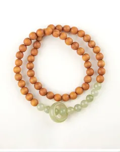 Macro view of double-strand sandalwood bracelet featuring pale green jade beads and ring
