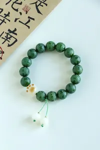 Macro detail of Six-Syllable Mantra engraved green beads with a cute cat paw pendant