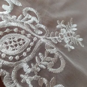 Close-up of white lace embroidery details on a fine mesh background for DIY home decor.