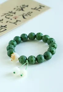 Detailed view of green bodhi bead bracelet with mantra carving and cat paw charm