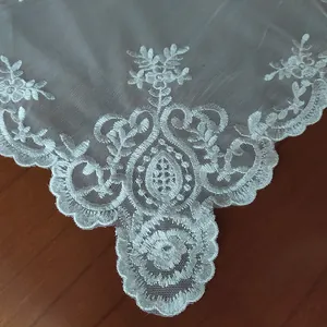 Macro detail of white lace tablecloth with floral embroidery on mesh fabric base