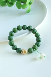 Close-up of green bodhi bracelet with six-character mantra and cat paw charm