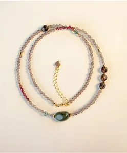 Detalle de un collar de cuarzo ahumado facetado natural con una piedra verde única