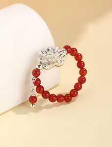 Primer plano de un anillo de cuentas de ágata roja con una flor de loto plateada
