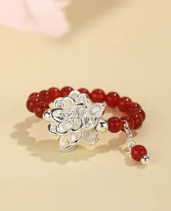 Primer plano de anillo de cuentas de cornalina roja con elegante dije de flor de plata 925