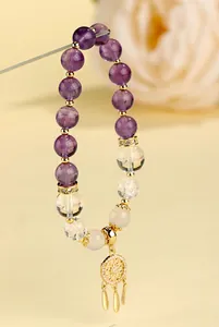 Detailaufnahme von Amethyst- und Bergkristall-Armband mit goldenem Traumfänger-Anhänger