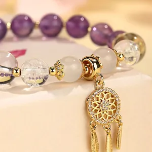 Handgefertigtes Armband aus weißem Kristall und Achat mit goldenem Traumfänger-Anhänger.