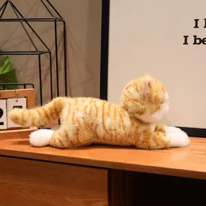 Peluche realistico di gatto soriano arancione sdraiato su un mobile in legno vista laterale