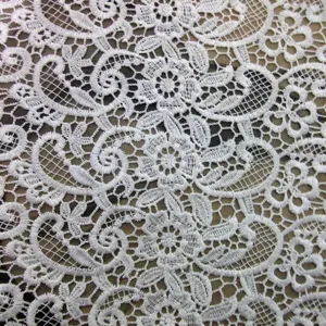 Macro view of white water-soluble lace fabric with intricate floral embroidery details