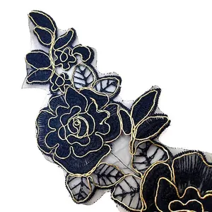 Macro detail of black floral lace embroidery with gold outlines on organza base