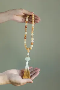 Detail view of handheld Bodhi prayer beads with a carved lotus charm and golden tassel