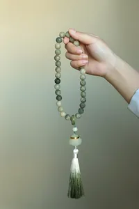 Detail of hand-held Buddhist prayer beads with carved lotus stones and a silk tassel.