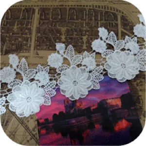 Detalle de encaje blanco soluble en agua con exquisitos motivos florales bordados a cordón