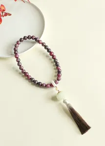 Close-up of Buddhist prayer beads with purple textured spheres and a long silk tassel