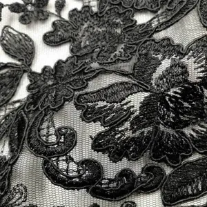 Κοντινό πλάνο μαύρης δαντέλας με περίπλοκο κέντημα λουλουδιών σε διάφανο δίχτυ