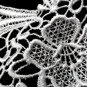 Detailed macro view of delicate white water-soluble lace embroidery texture on black