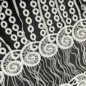 Dettaglio macro del pizzo idrosolubile in seta di latte bianca con frange eleganti