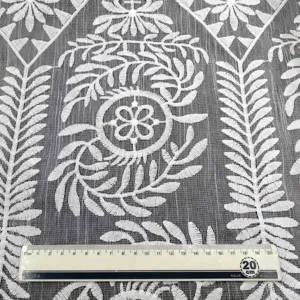 Vue détaillée d'une broderie en soie de lait blanche aux motifs floraux et feuilles délicats