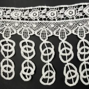 Dettaglio del bordo in pizzo bianco idrosolubile con ricamo a nappe in seta.