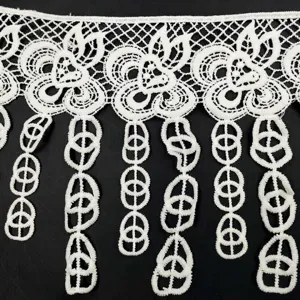 Macro view of white milk silk water-soluble floral lace trim with tassel pendants