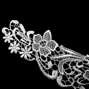 Macro detail of white water-soluble lace embroidery showing delicate floral patterns