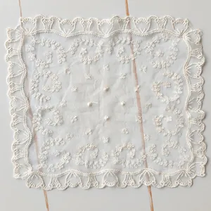 Detail of square white lace tablecloth with delicate floral embroidery and scalloped edges