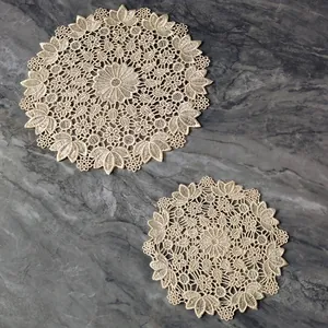Detailed view of beige round lace embroidered hollow-out coasters on marble background