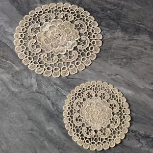 Detailed view of intricate cream lace embroidery on vintage style circular coasters.