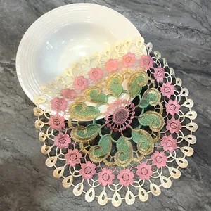 Detailed close-up of a colorful hollow-out lace placemat with floral embroidery on marble