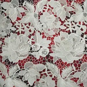 Detailed macro view of heavy white floral chemical lace embroidery on red background
