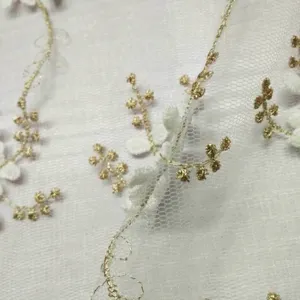 Vista macro dettagliata del ricamo floreale bianco con filo d'oro su pizzo a rete