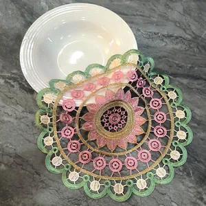 Detailed view of a round embroidered lace placemat with colorful floral patterns