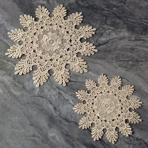 Close-up view of vintage beige lace embroidered coasters on a gray marble background.