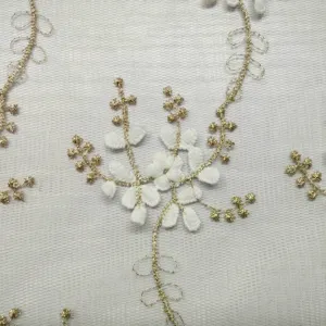 Dettaglio del ricamo floreale bianco e del filo dorato su un delicato tessuto a rete