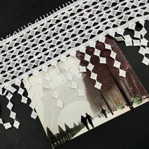 Detailansicht der weißen wasserlöslichen Milchseidenspitze mit eleganten Quasten