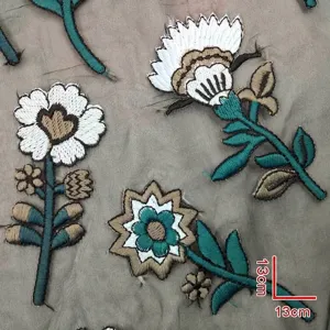 Detailed view of colorful floral embroidery patches on grey mesh with 13cm scale marks.