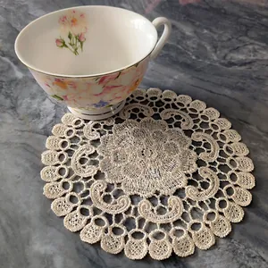 Intricate ivory lace embroidered circular coaster detail shown on elegant marble tabletop