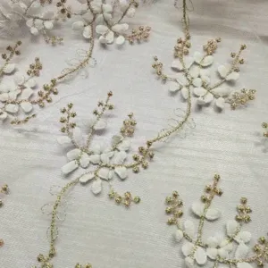 Primo piano dettagliato di ricamo floreale bianco e oro su tessuto di pizzo a rete