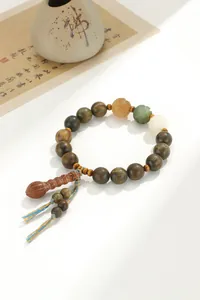 Détail d'un bracelet bouddhiste en bois de santal vert avec pompon ethnique