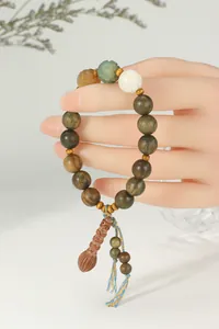 Gros plan d'un bracelet bouddhiste en bois de santal vert avec pompon en bois sculpté