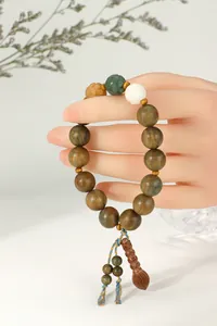 Détail du bracelet en bois de santal vert sur mannequin avec décor floral en arrière-plan