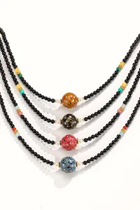 Macro detail of black onyx bead necklaces with handcrafted lacquer beads in four distinct colors.